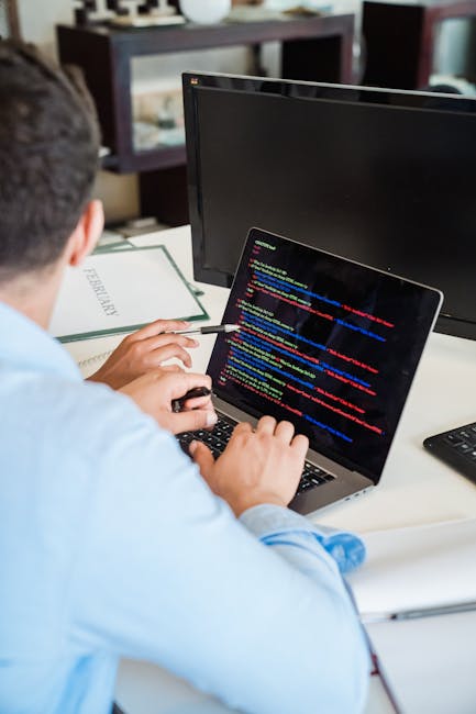 A close-up view of a laptop screen displaying lines of coding with color-coded syntax on the left side and a calculator interface on the right, featuring orange buttons for numbers and mathematical op